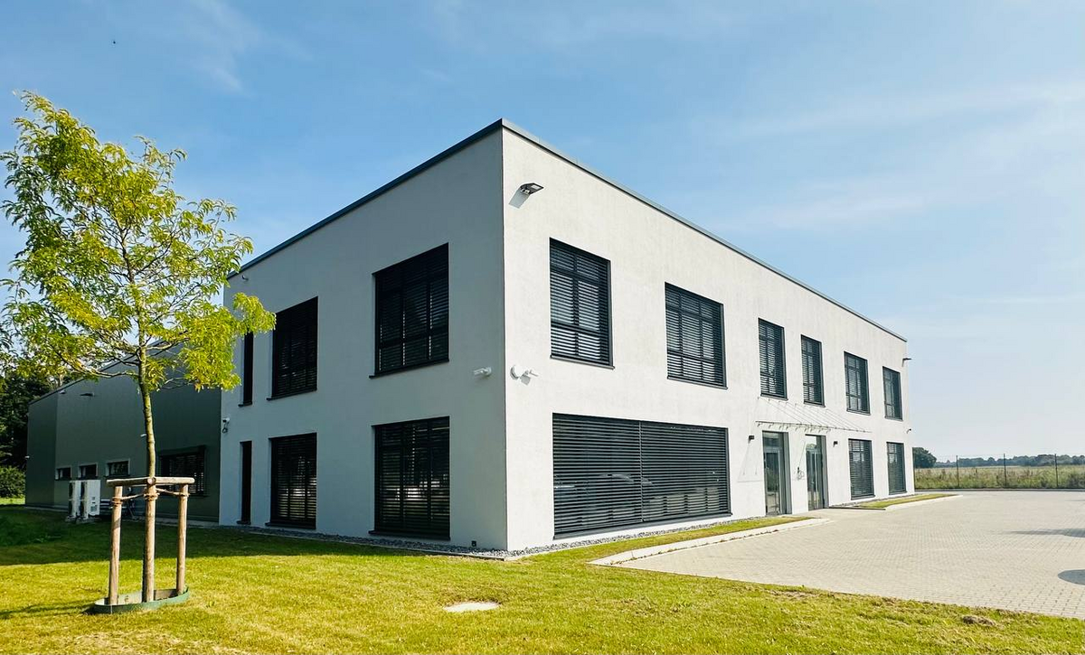Modernes Bürogebäude mit heller Fassade und großen Fenstern.