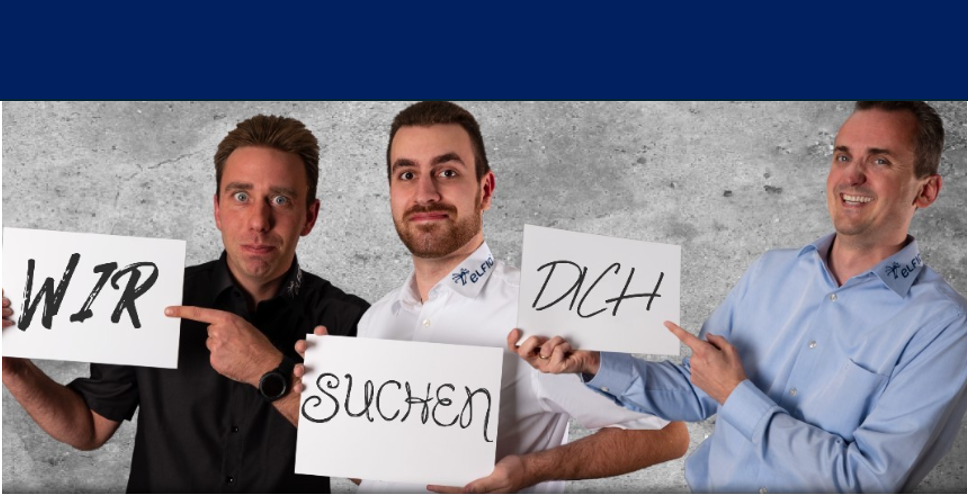 Drei Personen halten gemeinsam ein Schild mit dem Text „Wir suchen dich“.